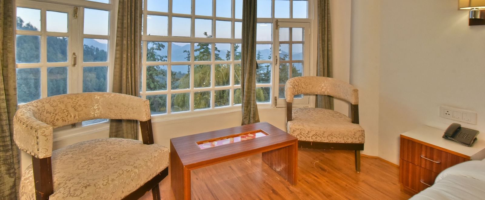 Seating area with two chairs placed next to the bed at DLS Hillcrest Resort, Shimla.